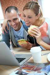 Roommates eating sandwich in front of laptop