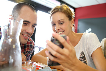 Young people in snack bar, connected on smartphone