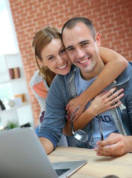 Cheerful couple websurfing on internet with laptop