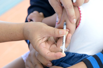 Doctor giving a child an intramuscular injection in arm, shallow