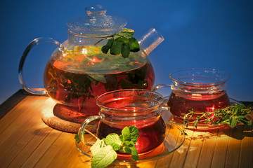Hot tea with curative herbs in teapot and cups