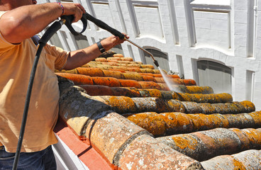 Worker cleaning a roof with high pressure water