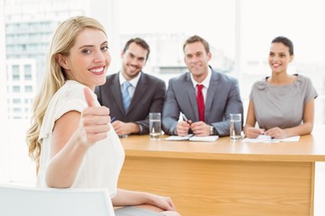 Woman gesturing thumbs up in front of corporate personnel office
