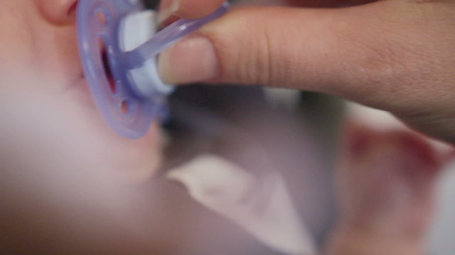 Little baby kid crying being given a blue pacifier