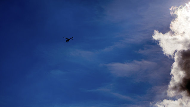 Helicopter flying away from the clouds
