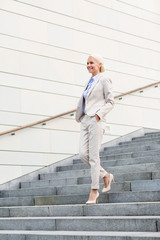 young smiling businesswoman walking down stairs