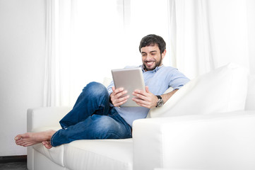 Young attractive Hispanic man at home using digital tablet pad