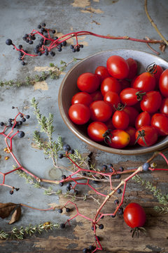 cherry tomatoes on bowl on table with branches and thyme sprigs