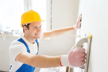 smiling builder with grinding tool indoors