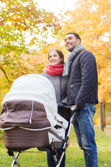 smiling couple with baby pram in autumn park