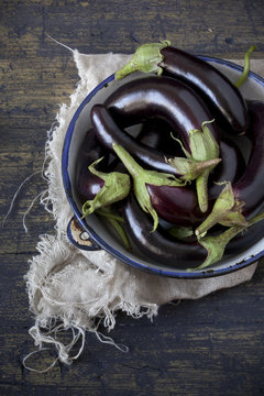 group of long eggplants on plate on table with frayed cloth