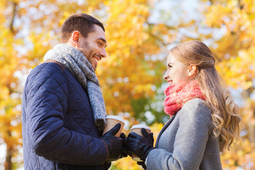 Fototapeta premium smiling couple with coffee cups in autumn park
