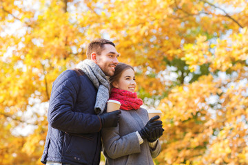 Fototapeta premium smiling couple with coffee cups in autumn park
