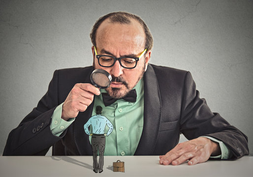 businessman looking at small employee through magnifying glass