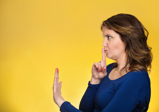 woman with finger on lips, shhh gesture asking be quiet