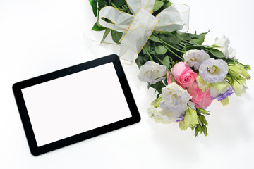 Tablet computer and bouquet of flowers on white background