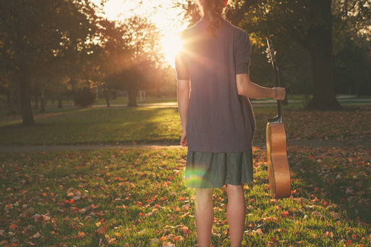 Woman with guitar at sunset in the park