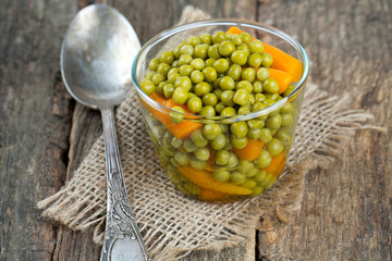 canned peas and carrots on wooden surface