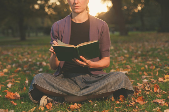 Woman reading in park at sunset