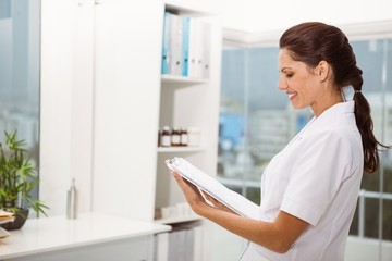 Smiling female doctor holding clipboard in medical office