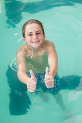 Little boy showing thumbs up in the pool
