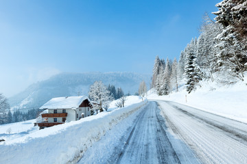 Morning winter misty rural alpine road and house