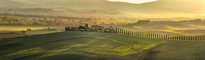Panoramic view of Tuscan house with cypress trees along the road