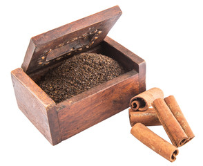 Dried, processed tea leaves in wooden box with cinnamon stick