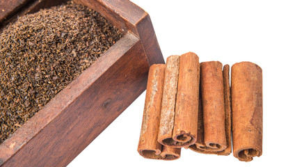 Dried, processed tea leaves in wooden box with cinnamon stick