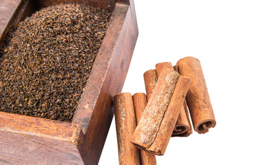 Dried, processed tea leaves in wooden box with cinnamon stick