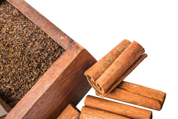 Dried, processed tea leaves in wooden box with cinnamon stick