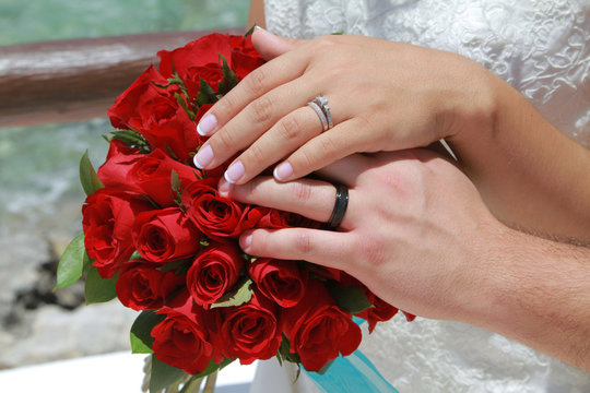 Wedding couple hands on red flowers
