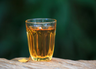 Yellow golden alcoholic drink in a brandy glass, on a wood table