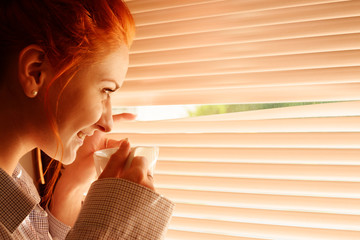 beautiful woman early in morning with cup of coffee at window