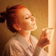 beautiful woman early in morning with cup of coffee at window