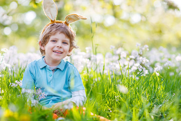 Cute happy little kid wearing Easter bunny ears at spring green