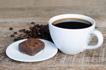 Black coffee with chocolate brownie on grained wood