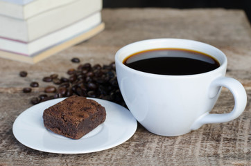 Black coffee with chocolate brownie on grained wood