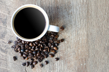 Black coffee with beans in on grained wood