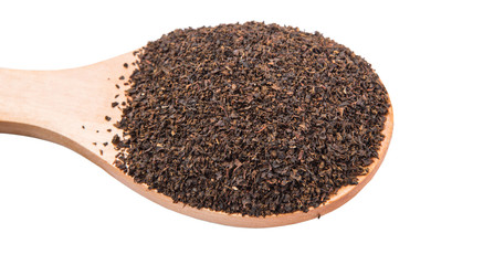 Dried, processed tea leaves in wooden spoon over white 