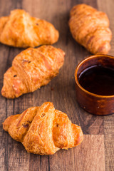 croissant with chocolate on a wooden board, coffee cup