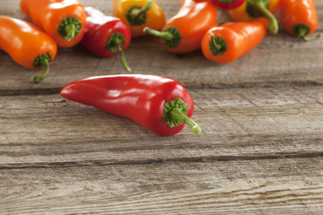 Red sweet pepper with other peppers on rough wood surface