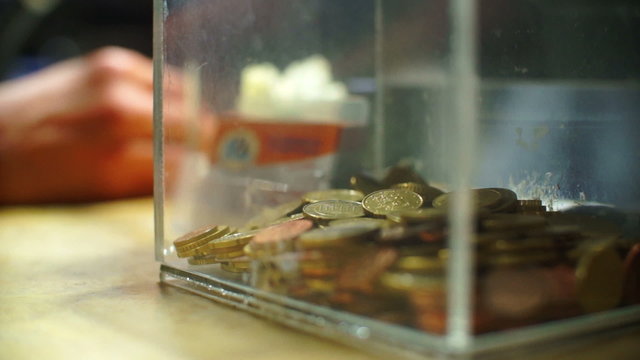 Man giving coins in tip box.