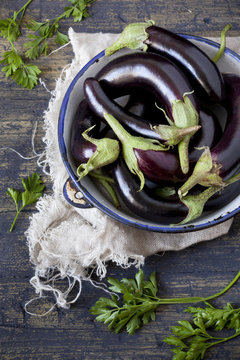 group of long eggplants on vintage plate on table with parsley