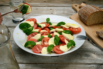 Caprese salad on white plate & vintage wooden desk