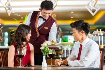 Abwaschbare Fototapete Restaurant Chinesischer Kellner serviert Abendessen in einem eleganten Restaurant oder Hotel