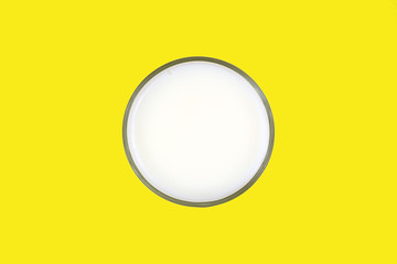 Glass of skim milk on a yellow background