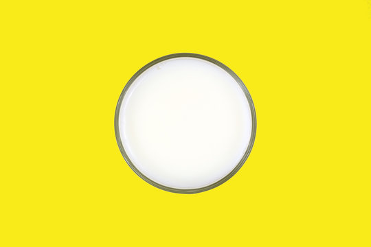 Glass of skim milk on a yellow background