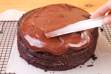 spreading chocolate ganache on the cake