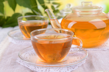 Teapot and cups of tea on table on bright background